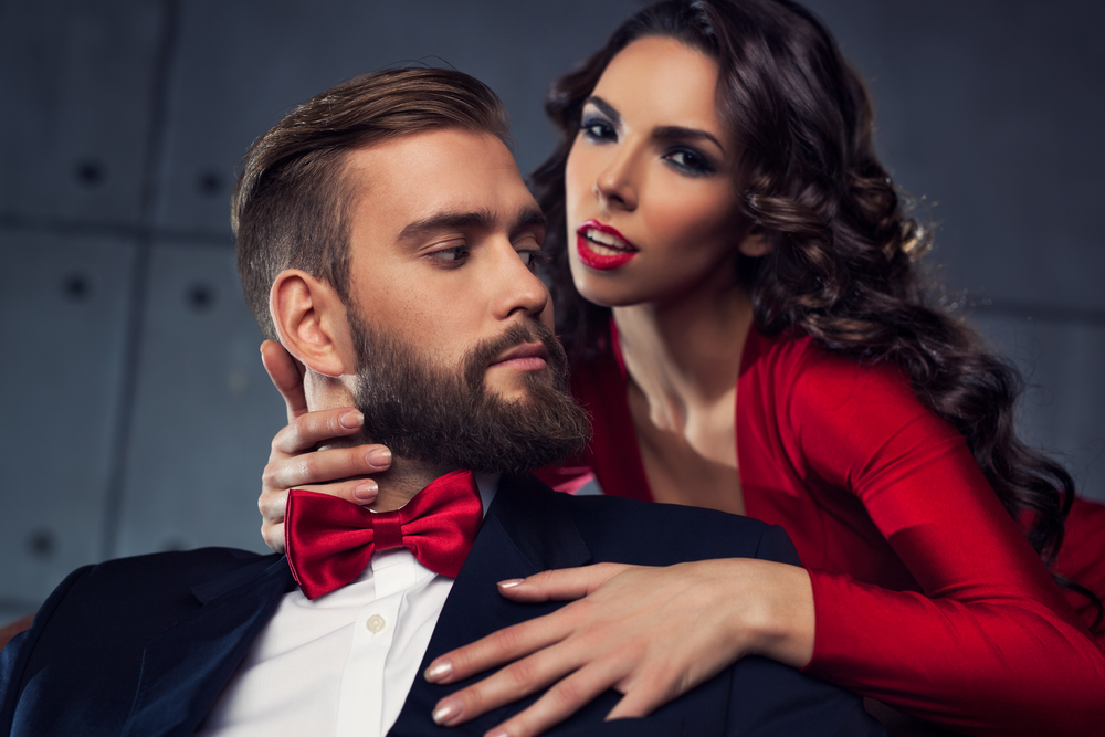 Young elegant couple portrait. Woman in red embrace man. Focus on man.